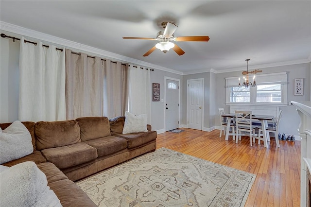 living area with baseboards, light wood-style flooring, crown molding, and ceiling fan with notable chandelier