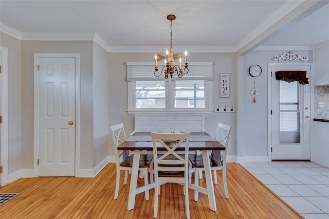 dining room with light wood finished floors, a chandelier, baseboards, and ornamental molding