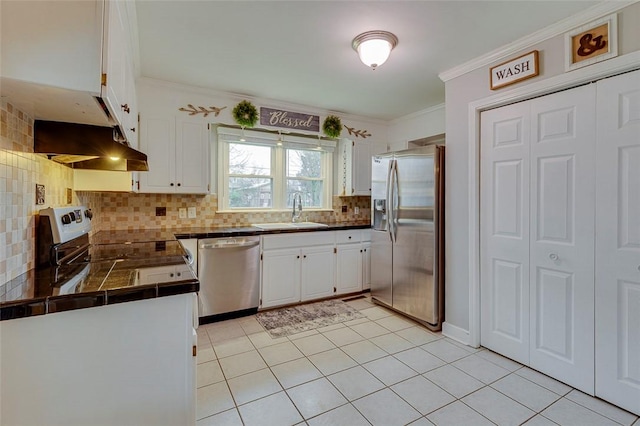 kitchen with a sink, ornamental molding, stainless steel appliances, white cabinets, and under cabinet range hood