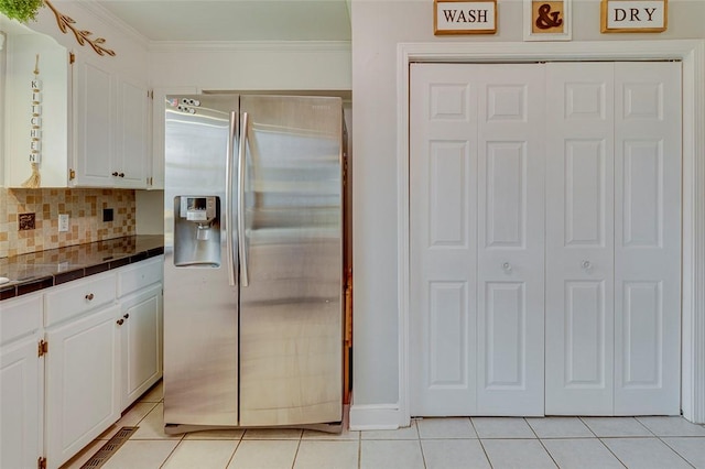 kitchen with light tile patterned floors, decorative backsplash, stainless steel fridge, and white cabinets