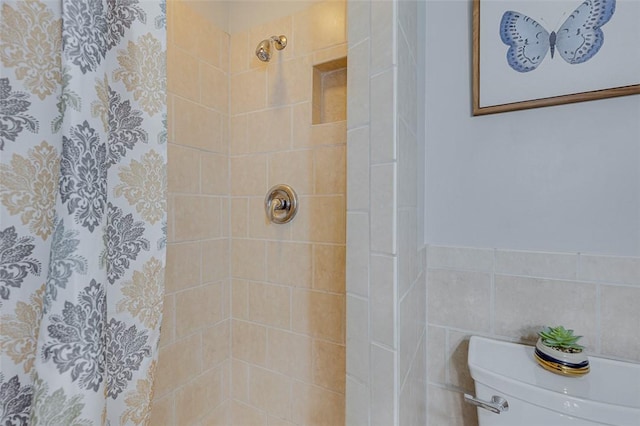 bathroom featuring toilet, tile walls, wainscoting, and a tile shower