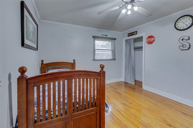 bedroom featuring a closet, baseboards, hardwood / wood-style floors, and crown molding