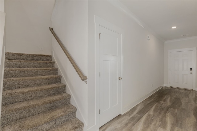 staircase with recessed lighting, wood finished floors, baseboards, and ornamental molding