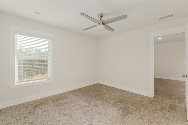 empty room with visible vents, ceiling fan, baseboards, and carpet