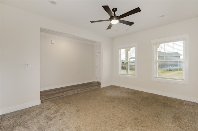 carpeted empty room featuring a ceiling fan and baseboards