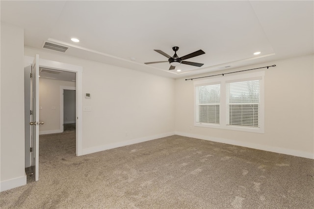 carpeted empty room featuring visible vents, recessed lighting, a raised ceiling, and baseboards