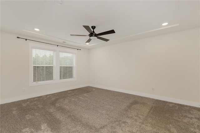 spare room featuring a tray ceiling, baseboards, and carpet flooring