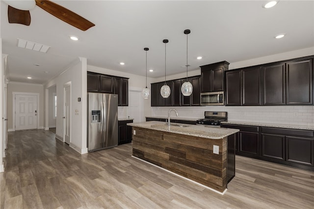 kitchen with a sink, decorative backsplash, appliances with stainless steel finishes, and wood finished floors