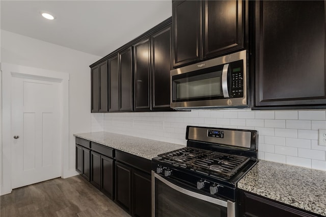 kitchen with dark wood-type flooring, light stone counters, tasteful backsplash, and stainless steel appliances