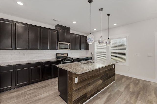 kitchen with visible vents, a sink, backsplash, light wood-style floors, and appliances with stainless steel finishes