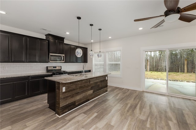 kitchen featuring a sink, decorative backsplash, light wood-style flooring, and stainless steel appliances