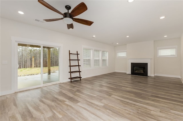 unfurnished living room featuring recessed lighting, a fireplace with flush hearth, wood finished floors, and visible vents