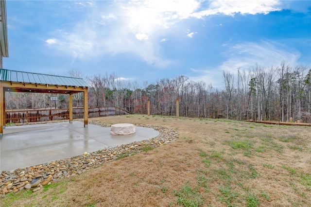 view of yard featuring a forest view, fence, and a patio area