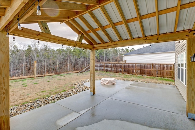 view of patio with a gazebo, a wooded view, and fence