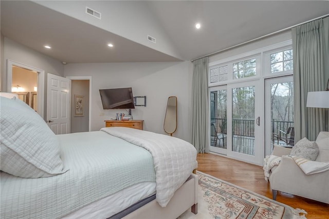 bedroom with access to exterior, visible vents, lofted ceiling, and wood finished floors