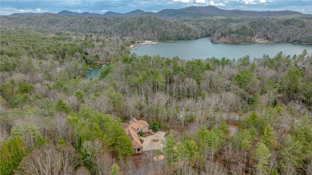 drone / aerial view with a water and mountain view and a wooded view