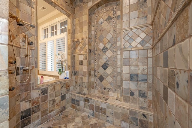 bathroom featuring visible vents, a tile shower, and stone finish flooring