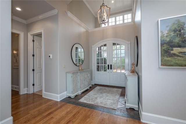 entryway with ornamental molding, wood finished floors, french doors, an inviting chandelier, and baseboards