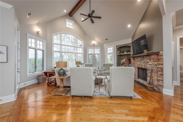 living area with a wealth of natural light, visible vents, a stone fireplace, and wood finished floors