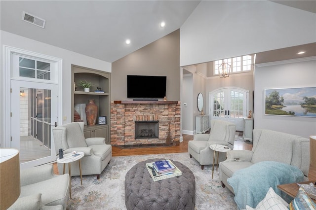 living area featuring visible vents, built in features, wood finished floors, french doors, and a fireplace