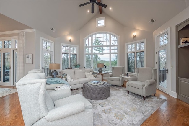 living room with wood finished floors, visible vents, and high vaulted ceiling