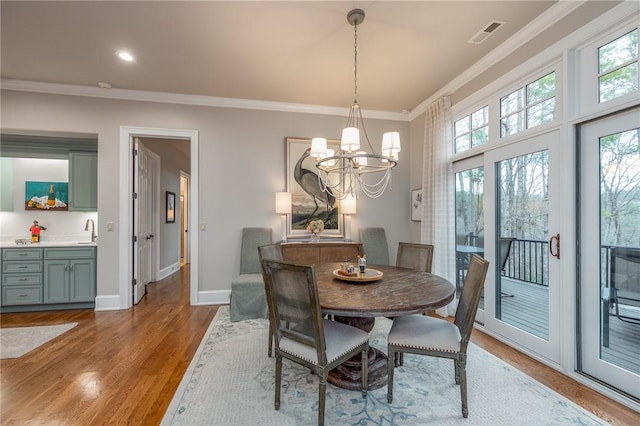 dining space with visible vents, ornamental molding, wood finished floors, an inviting chandelier, and baseboards