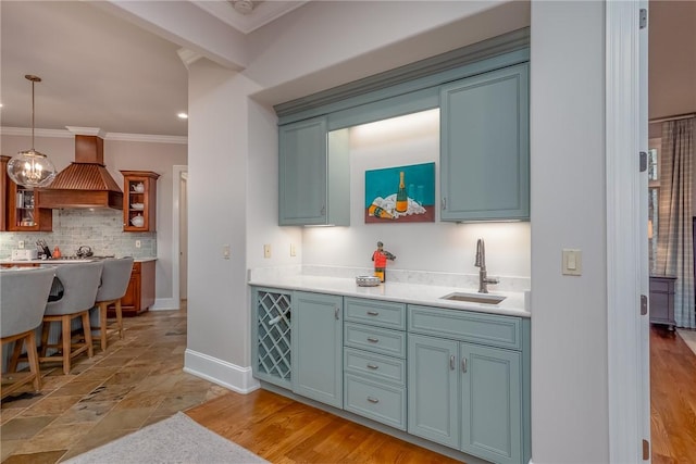 kitchen with baseboards, ornamental molding, a sink, custom range hood, and backsplash