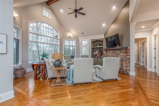 living room featuring visible vents, baseboards, a fireplace, light wood-style floors, and high vaulted ceiling