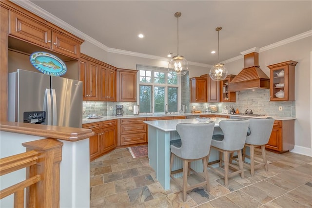 kitchen with stainless steel fridge, brown cabinets, light countertops, and custom range hood