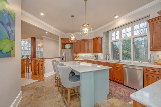 kitchen with light countertops, ornamental molding, decorative backsplash, stainless steel appliances, and a sink