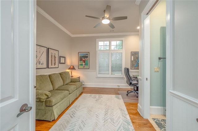 office space with light wood finished floors, a ceiling fan, baseboards, and ornamental molding