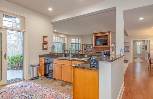 kitchen featuring dark stone counters, a peninsula, recessed lighting, a sink, and dishwasher