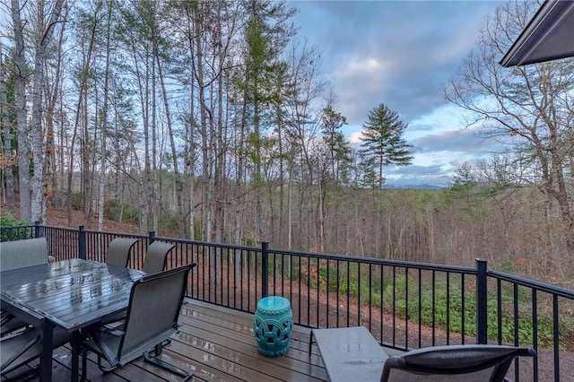 deck featuring outdoor dining space and a forest view