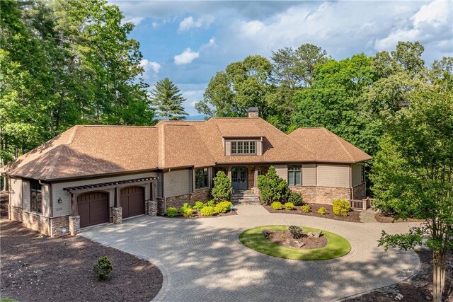 104 Sweetshrub Way, Sunset, SC 29685 - craftsman-style home with stone siding, curved driveway, an attached garage, a chimney, and a shingled roof