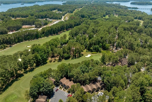 aerial view with a wooded view, view of golf course, and a water view