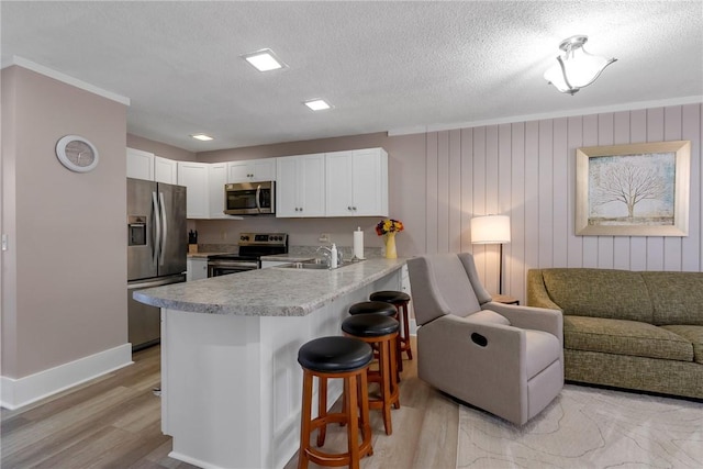 kitchen featuring a breakfast bar, a peninsula, a sink, stainless steel appliances, and open floor plan