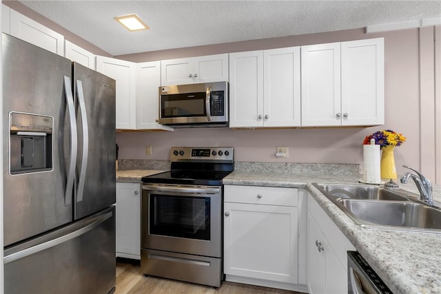 kitchen with white cabinets, appliances with stainless steel finishes, light countertops, and a sink