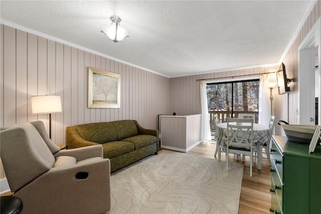 living room featuring crown molding, light wood-type flooring, and a textured ceiling