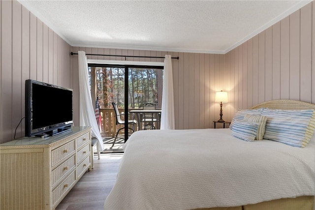 bedroom featuring access to exterior, ornamental molding, a textured ceiling, and wood finished floors