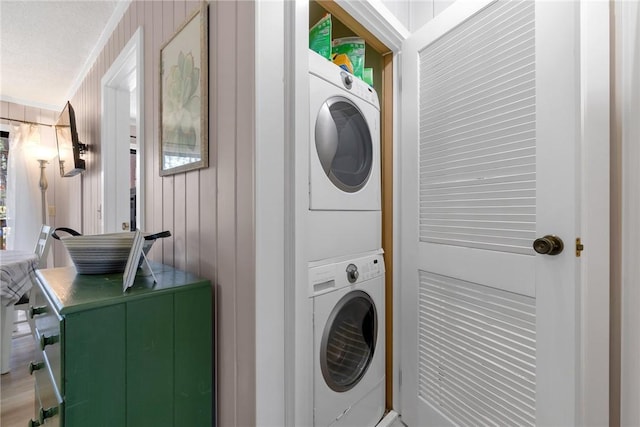 laundry area featuring laundry area, stacked washer and clothes dryer, and wooden walls