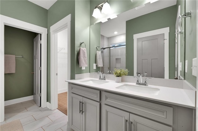 bathroom with double vanity, baseboards, a stall shower, and a sink