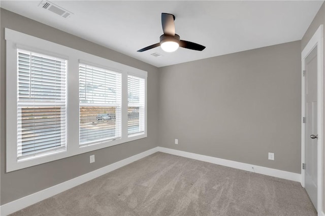 carpeted spare room with a ceiling fan, baseboards, and visible vents