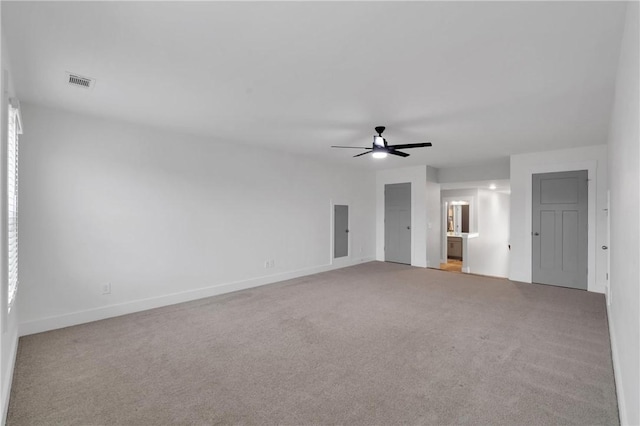 carpeted spare room featuring a ceiling fan, visible vents, and baseboards