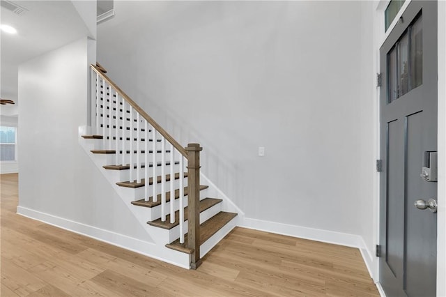 staircase featuring visible vents, baseboards, and wood finished floors