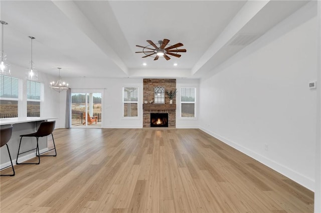 unfurnished living room with baseboards, a raised ceiling, light wood-style floors, and a fireplace