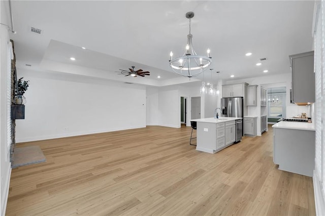 kitchen featuring visible vents, light countertops, a kitchen bar, a raised ceiling, and open floor plan