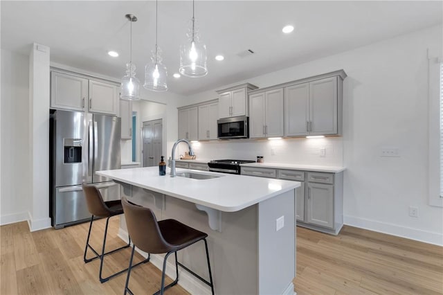 kitchen featuring a sink, backsplash, appliances with stainless steel finishes, and gray cabinets