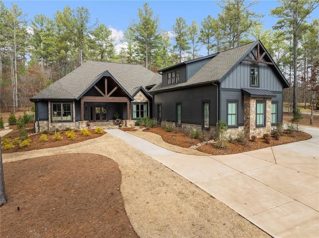 view of front of house with stone siding, board and batten siding, driveway, and a shingled roof