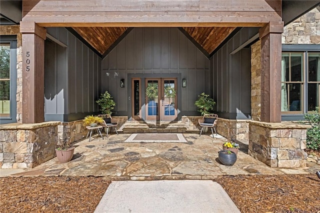 entrance to property featuring french doors, board and batten siding, and stone siding