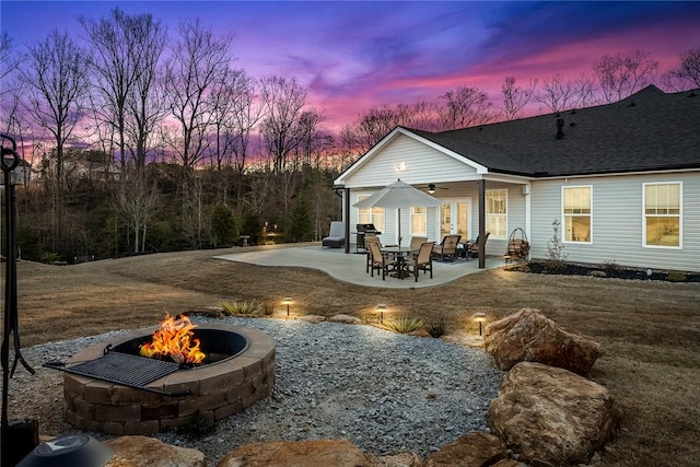 rear view of house featuring a ceiling fan, a patio area, a shingled roof, and a fire pit